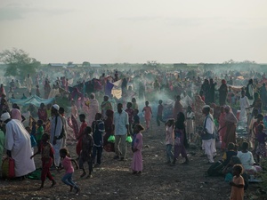 A large number of new arrivals from Sudan wait in a field in South Sudan