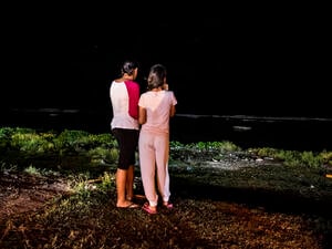 Night time. Two young women look out to sea.