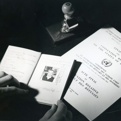 A black and white photo showing travel documents and The Convention Relating to the Status of Refugees.