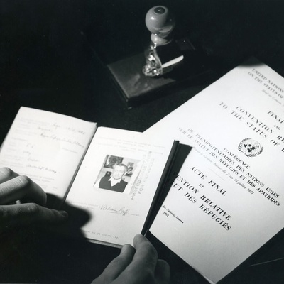 A black and white photo showing travel documents and The Convention Relating to the Status of Refugees.