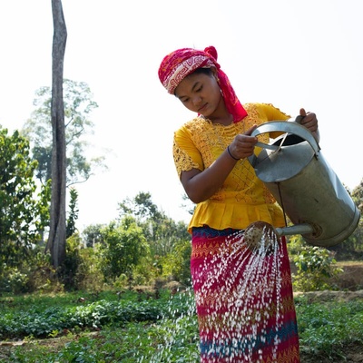 A young woman waters vegatables