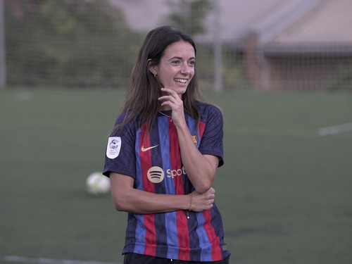 Aitana Bonmatí in football attire smiling on the football field