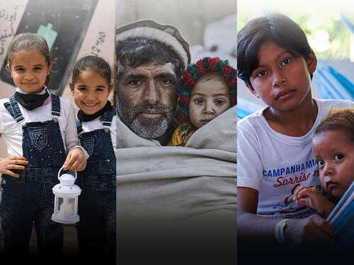 Two young refugees sit at their classroom desks and smile into the camera