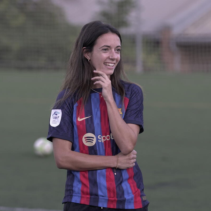Aitana Bonmatí in football attire smiling on the football field