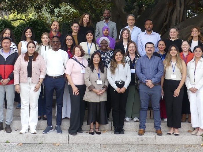 A large group of people pose for a photo on some steps under some large trees