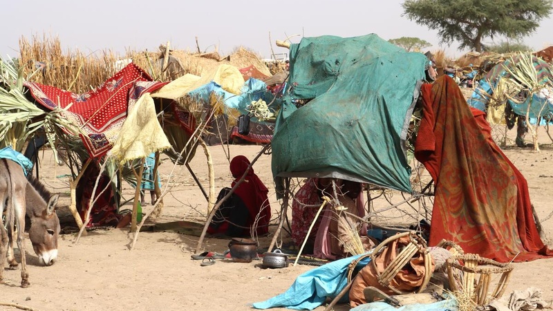 Sudanese refugees sit in the shade under makeshift shelters in the Chadian desert