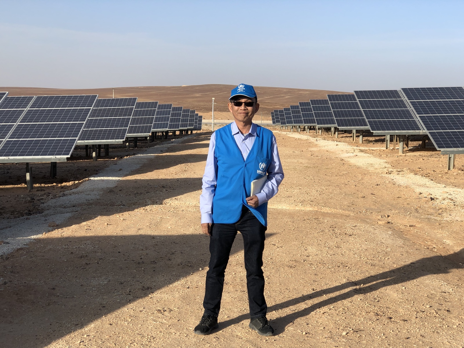 Mr. Wanchai Tachavejnukul standing in the middle of a solar panel field.