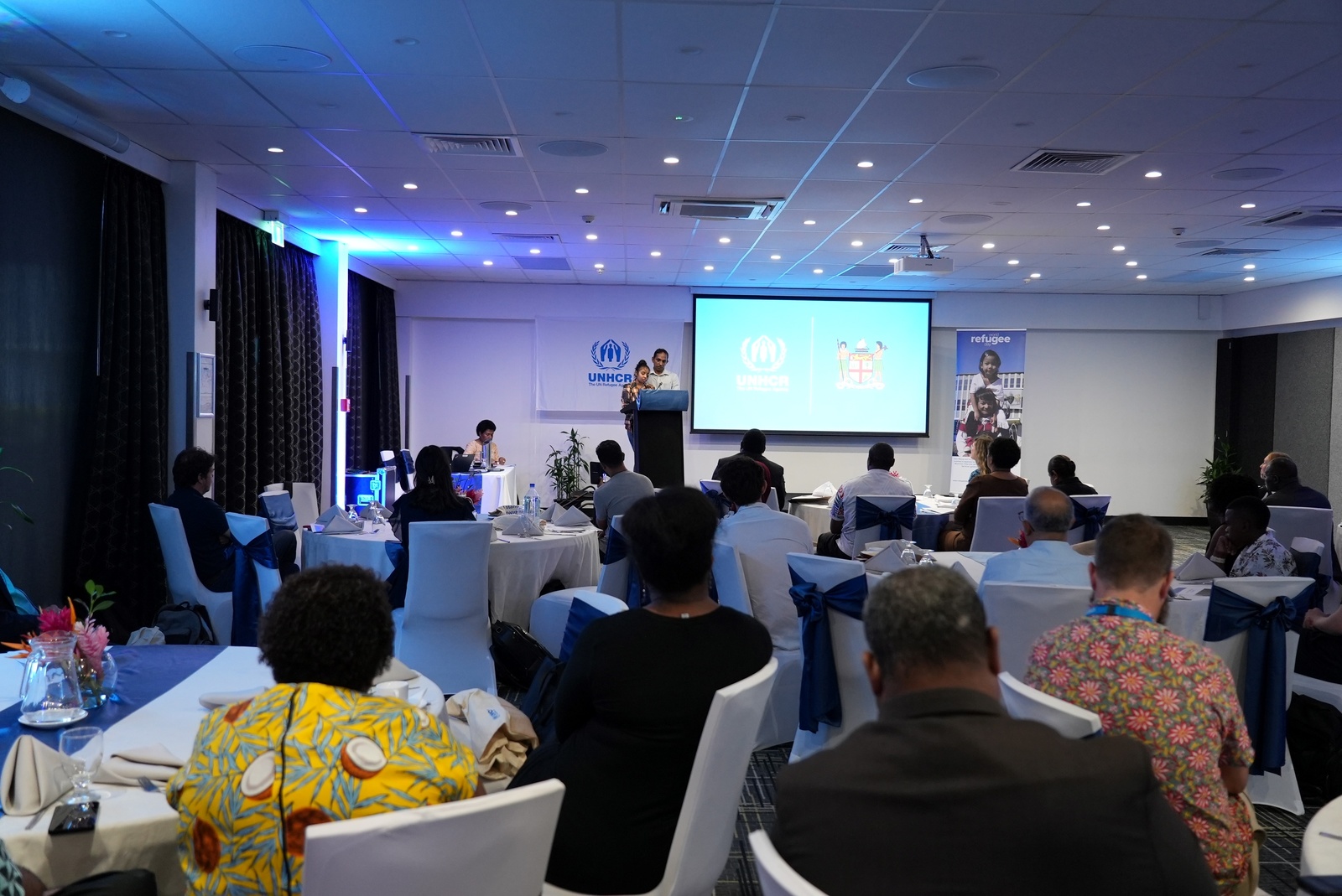 Guests sit and listen to refugees describe their positive experience in Fiji