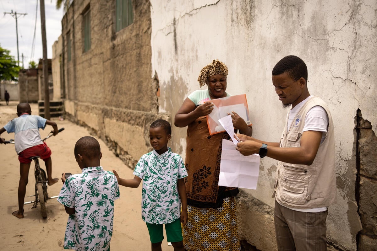A smiling woman has her papers checked while her sons play nearby