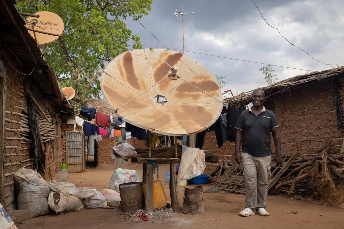 John Songa, de 51 años, refugiado de la República Democrática del Congo, junto al satélite para televisión que instaló en su patio.