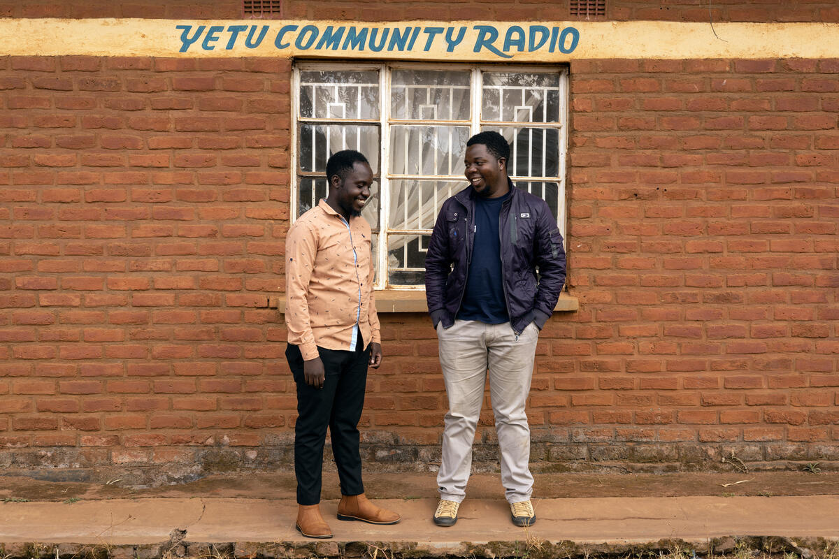 Two smiling men outside the Yetu Community Radio building