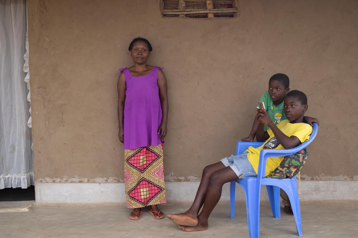 Neema Cenga, quien llegó a Mozambique en 2003 tras huir de la violencia en la República Democrática del Congo, con dos de sus ocho hijos frente a su casa en el asentamiento de refugiados de Marratane.