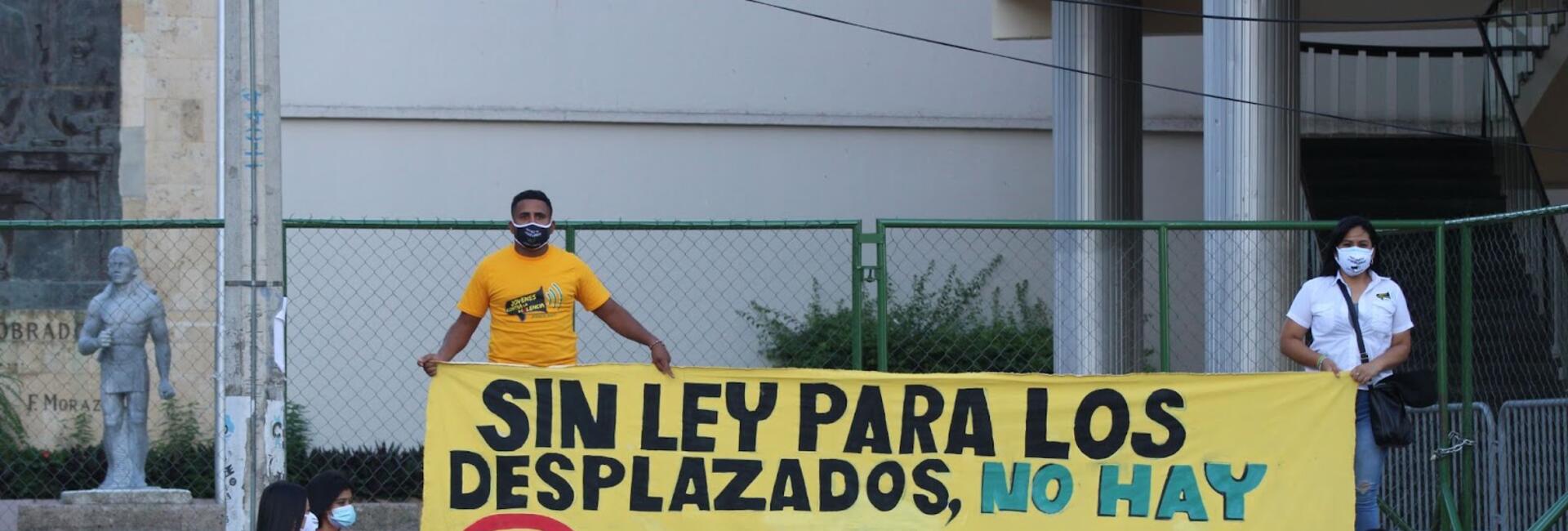 Protesters holding a banner saying "no law for displaced persons, no vote for deputies" (translated from Spanish)