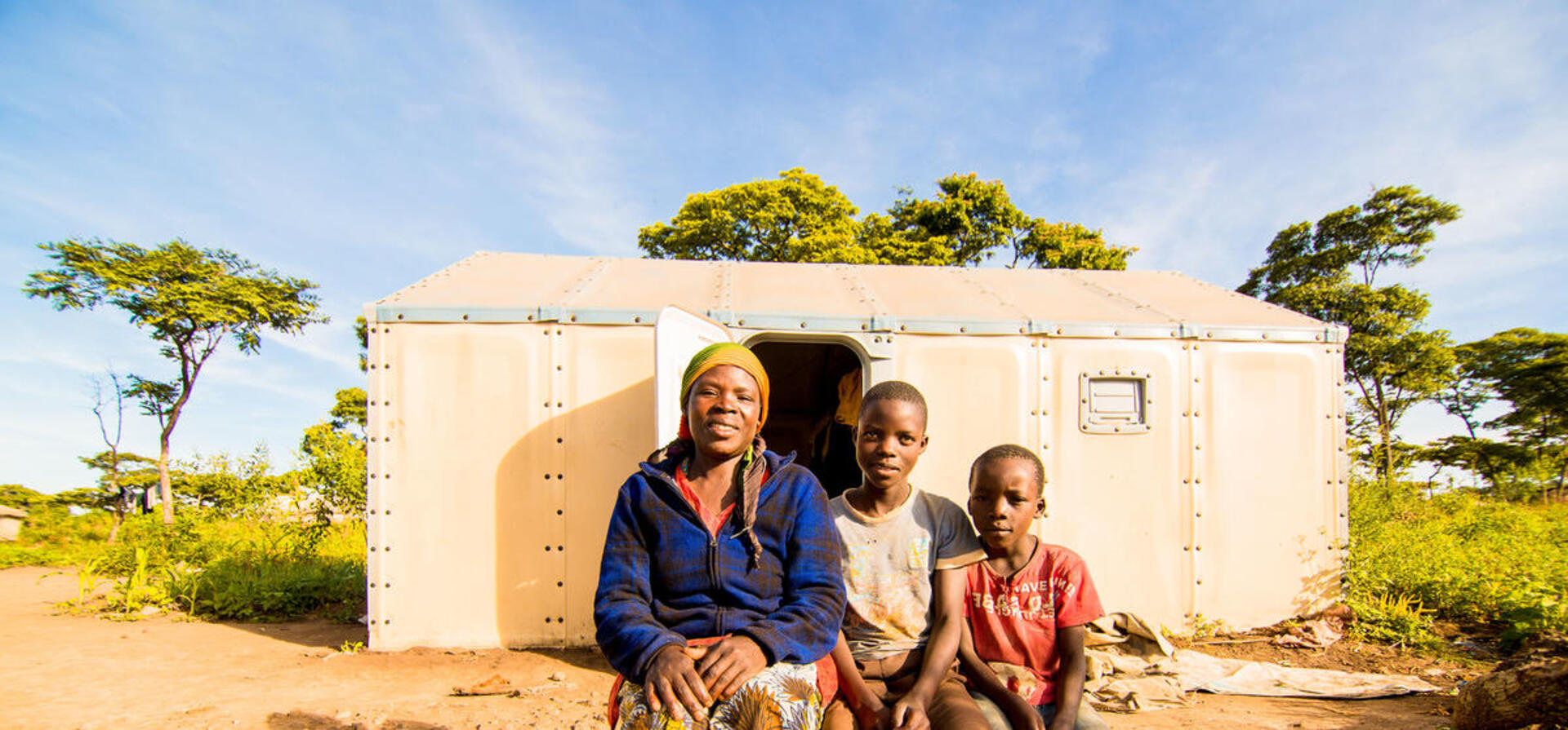 Tanzania. Velarie Ntahonicaye and her family with their Refugee Housing Unit (RHU) in Kigoma refugee Camp
