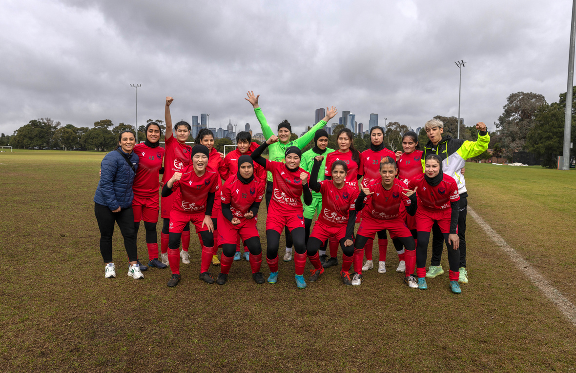 A women's football team gathers for a group portrait on a football field.