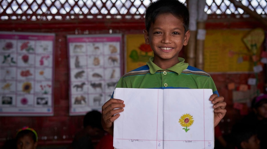 Mohammad holds a picture of a yellow flower he drew at a learning center in the Kutupalong camp for Rohingya refugees, Bangladesh.