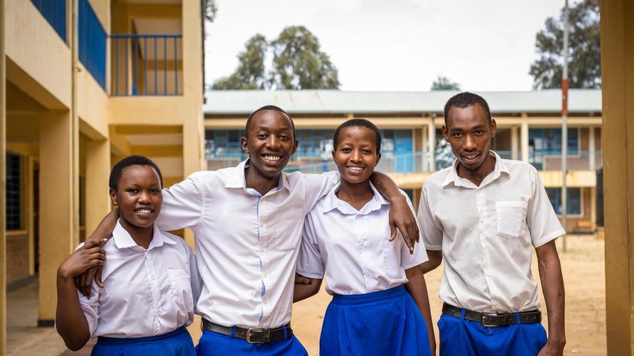 Four smiling students from the Democratic Republic of the Congo stand outside with their arms around each other 