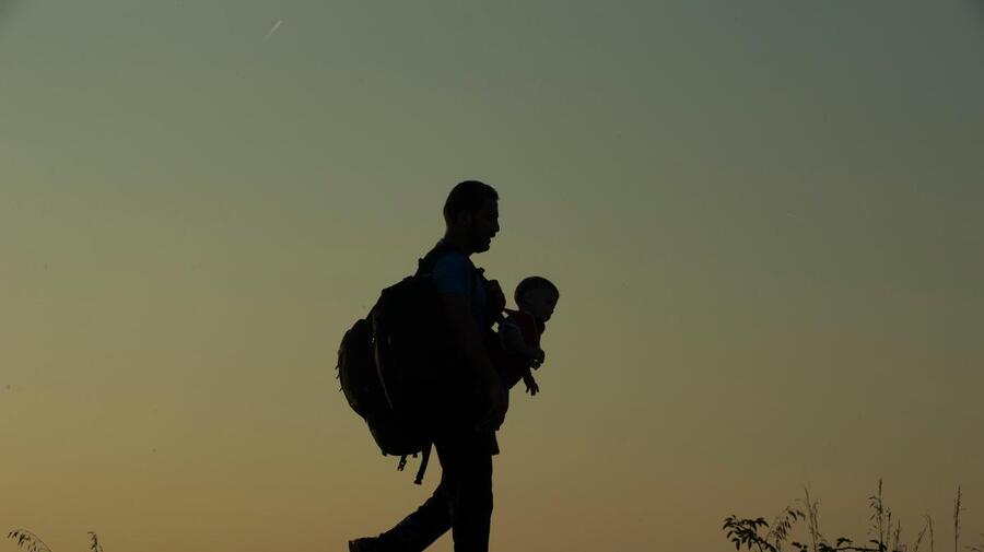 Hungary. Refugees father walking along rail tracks just after crossing the border