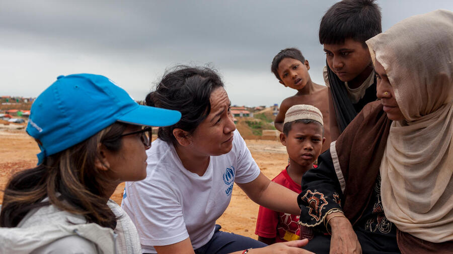 Outside. A women and three children talk with two UNHCR staff.