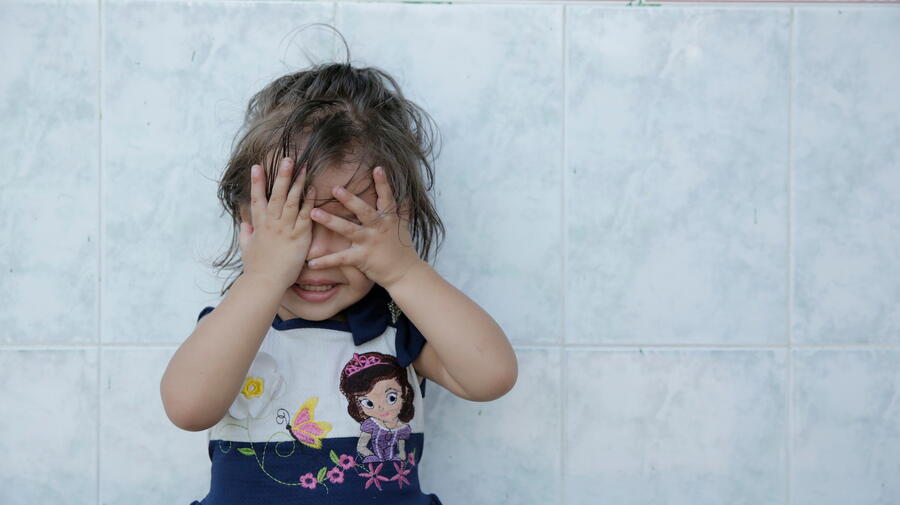 A young girl cover her eyes with her hands