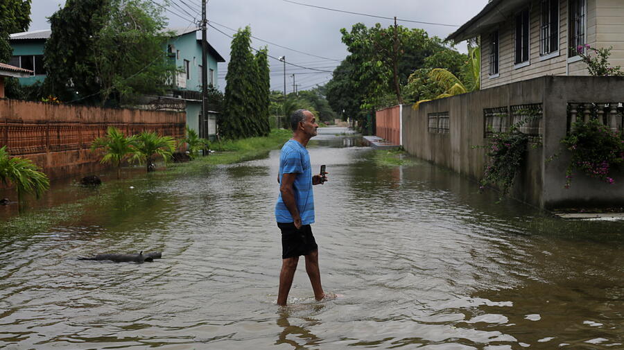A man walks through a flooded street in Tela, Honduras as Hurricane Eta approaches (3 November, 2020).