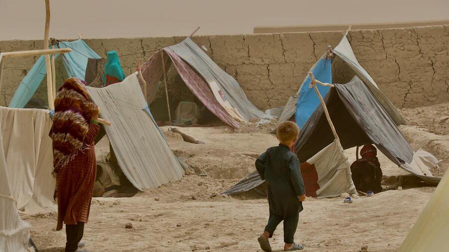 A woman and child walk between the makeshift tents in Nawabad Farabi-ha camp for internally displaced people in Mazar-e Sharif in northern Afghanistan.