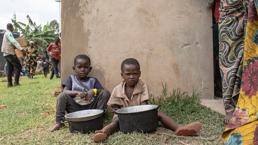 Dos niños esperan por comida en el centro de tránsito de Nyakabande en Kisoro, Uganda, después de unirse a miles de personas que huyen de los combates en el territorio de Rutshuru, en la República Democrática del Congo, a principios de noviembre.