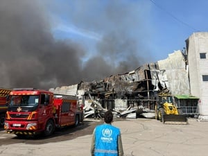 Photo d'un employé du HCR devant un entrepôt en feu