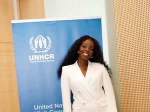Jeny BSG standing in front of UNHCR banner