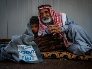 Jordan. Hassan 55 years old syrian refugee cuddling his 5 years old grandson with UNHCR blanket