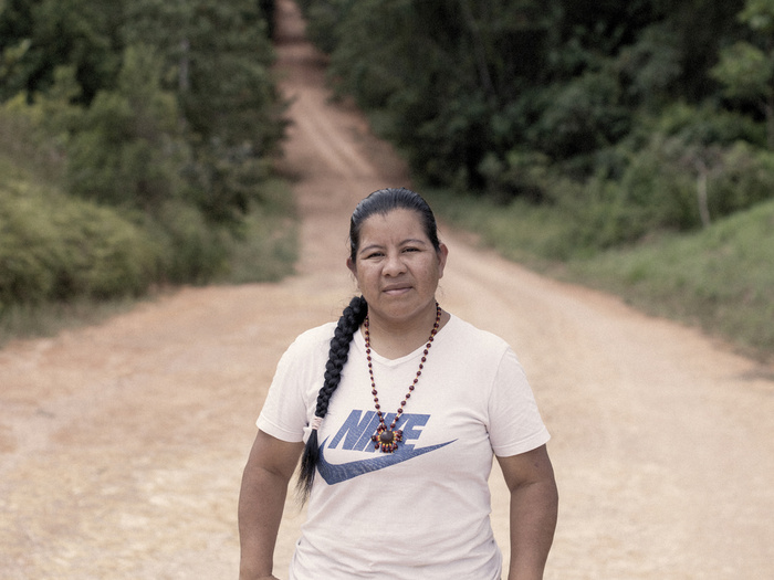 Une femme se tient sur un chemin de terre qui traverse une forêt