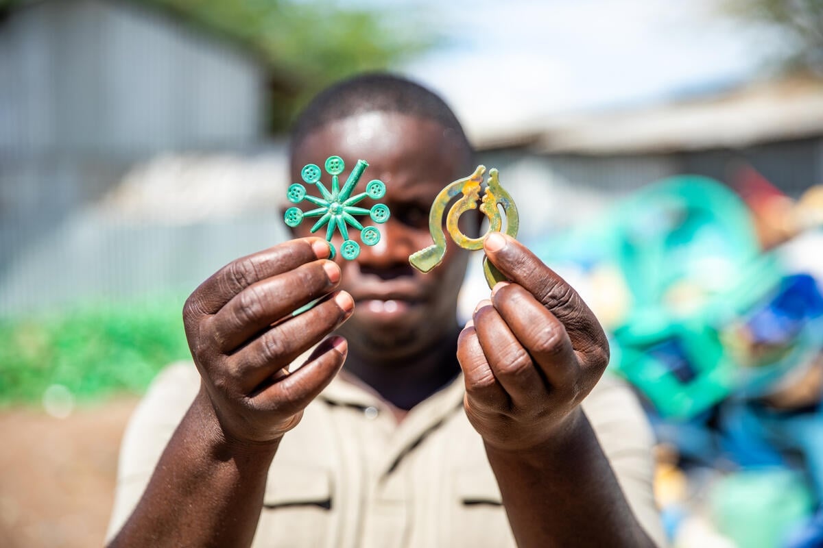 Un homme montre des boutons et des patères fabriqués à partir de déchets plastiques recyclés. 