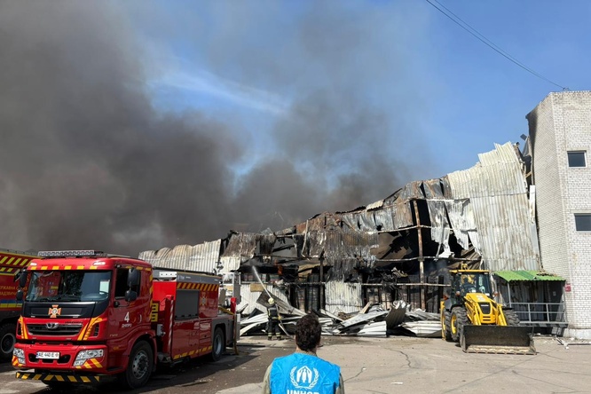 Photo d'un employé du HCR devant un entrepôt en feu