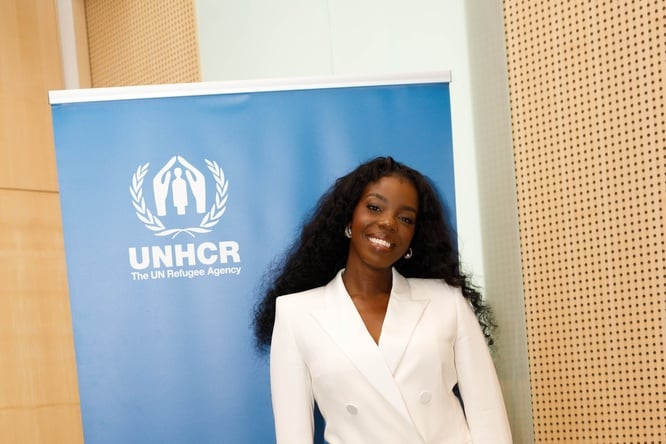 Jeny BSG standing in front of UNHCR banner