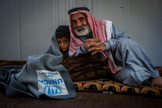 Jordan. Hassan 55 years old syrian refugee cuddling his 5 years old grandson with UNHCR blanket
