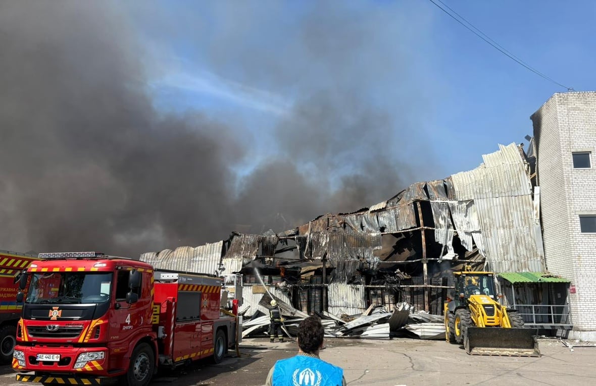 Photo d'un employé du HCR devant un entrepôt en feu