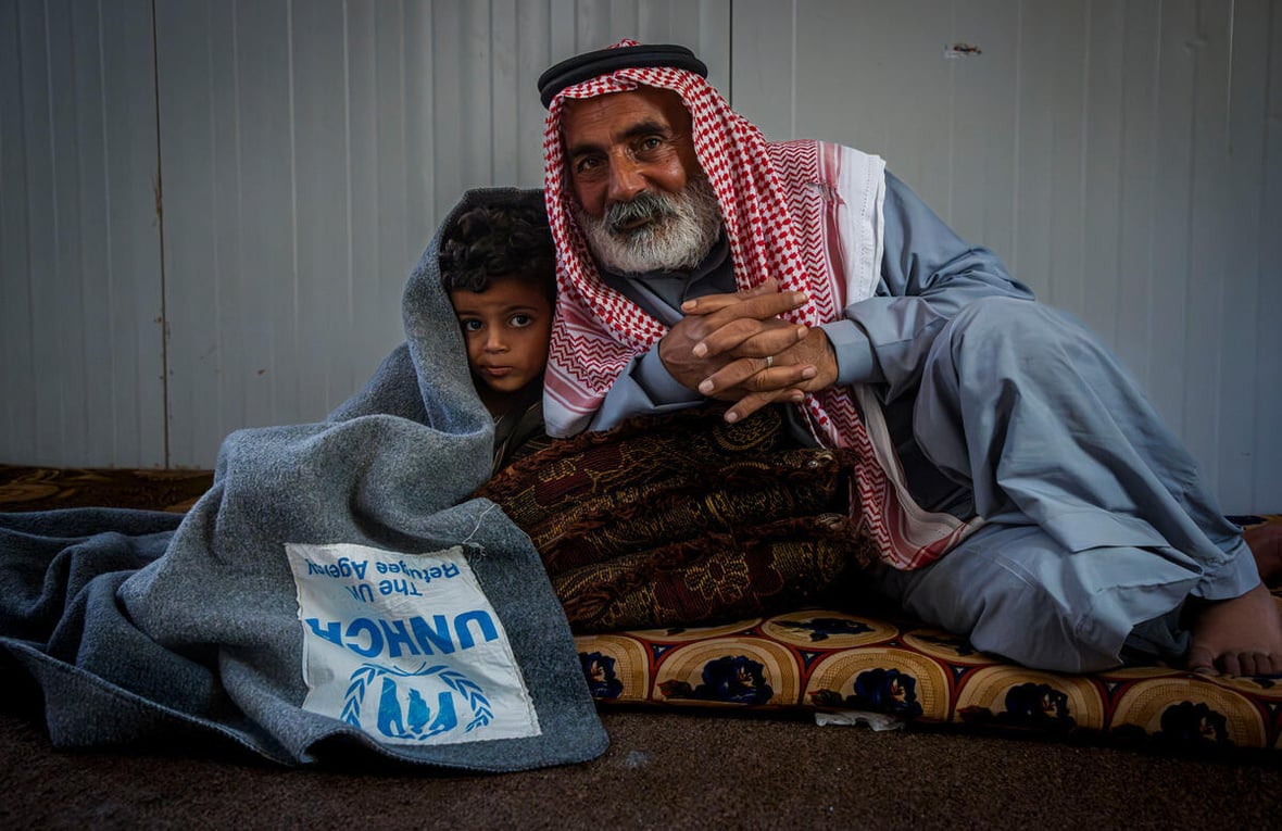 Jordan. Hassan 55 years old syrian refugee cuddling his 5 years old grandson with UNHCR blanket