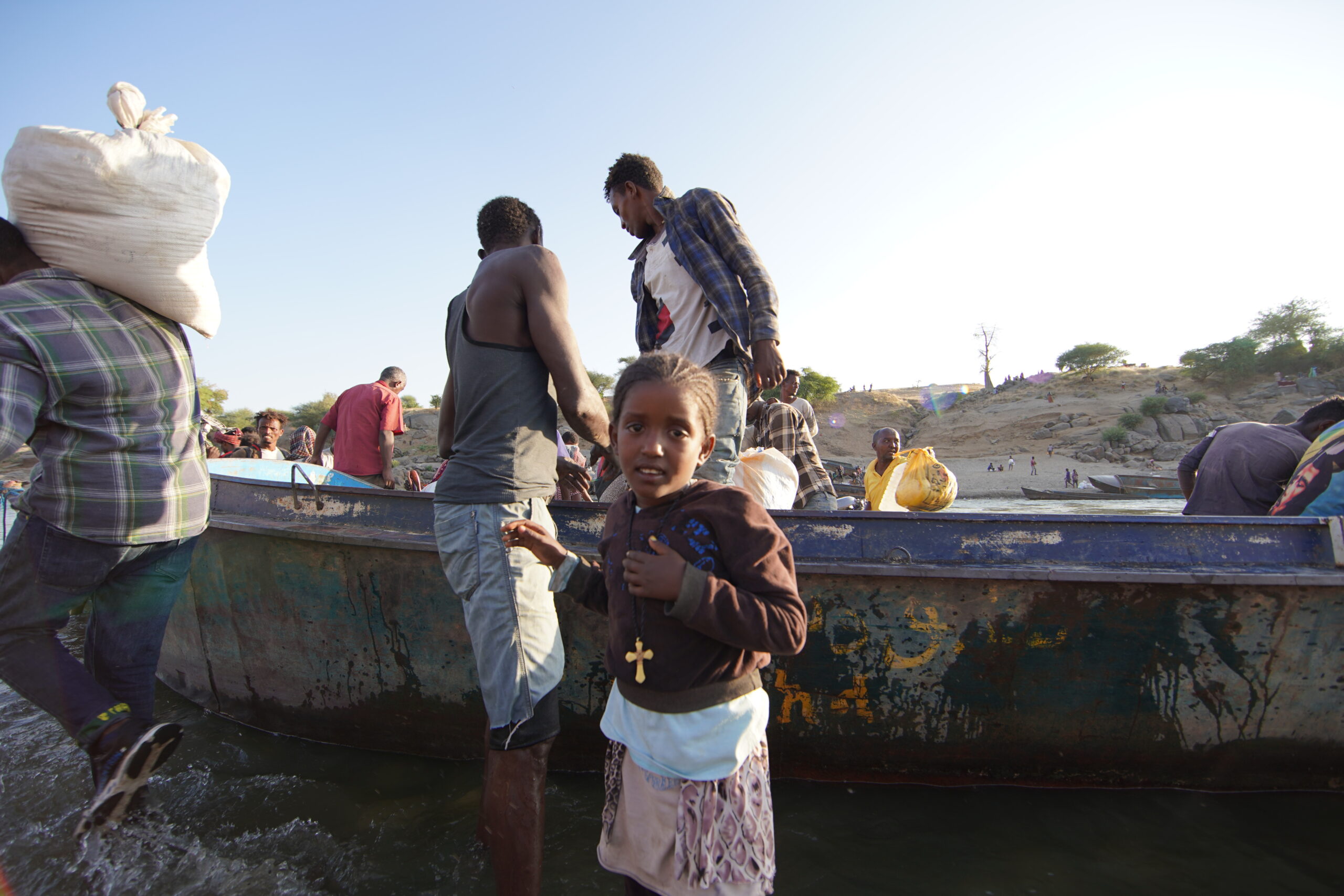 Des réfugiés éthiopiens ayant fui les violences dans la région du Tigré déchargent un bateau sur la rivière Tekezé, après avoir traversé la frontière soudanaise près de Hamdayet.