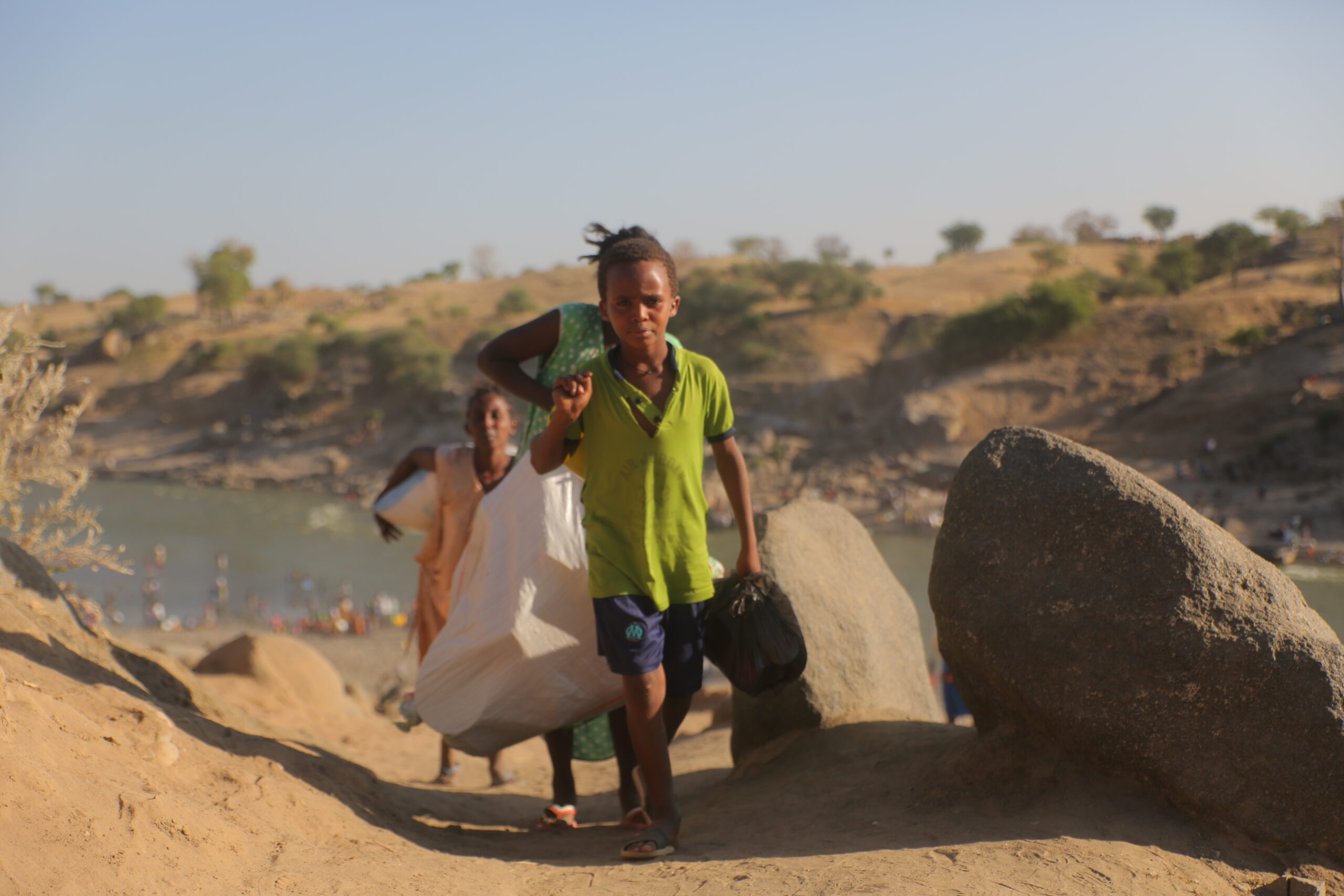 Des réfugiés éthiopiens ayant fui les violences dans la région du Tigré déchargent un bateau sur la rivière Tekezé, après avoir traversé la frontière soudanaise près de Hamdayet.