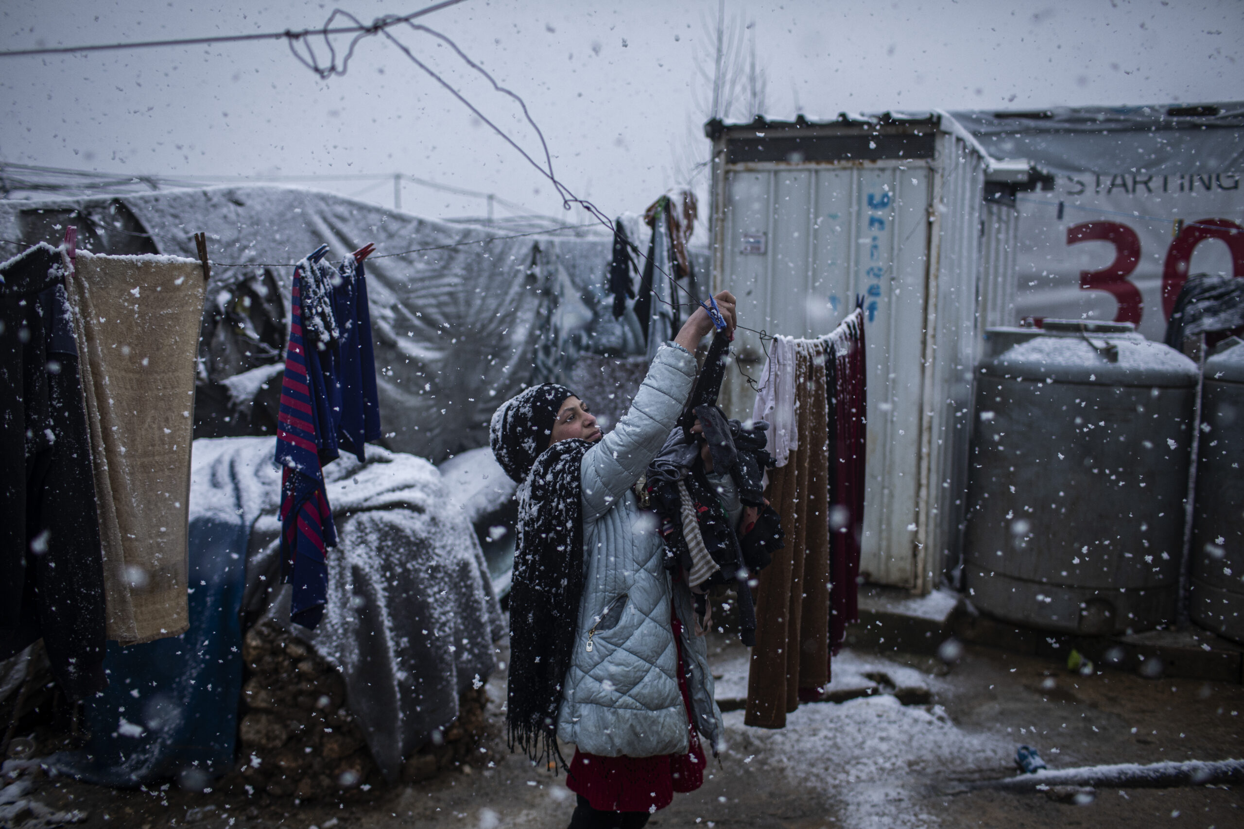 Siba Issa El Ali, een 10 jaar oud Syrisch vluchtelingenmeisje uit Deir ez-Zor, haalt de kleren van de waslijnen tijdens de sneeuwstorm die in een informeel vluchtelingenkamp waar zij verblijft in de Bekavallei woedt. ©UNHCR/Diego Ibarra Sánchez