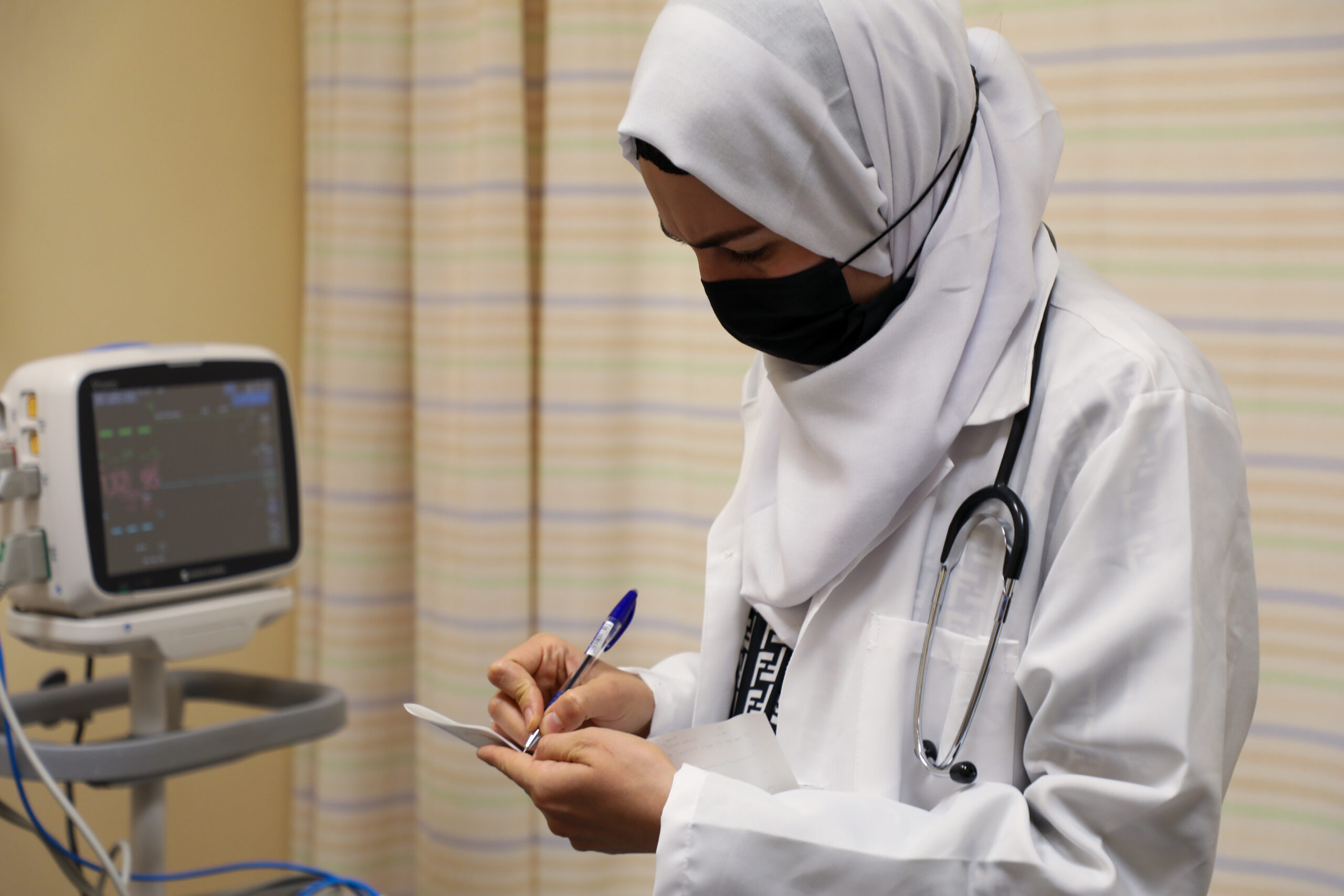 Dr Israa, een Irakese vluchtelinge en gediplomeerd arts, onderzoekt een patiënt in het AlBashir ziekenhuis in Amman. Ze werkt sinds kort mee met UNHCR om de COVID-19-respons in Jordanië te ondersteunen. © UNHCR/Lilly Carlisle