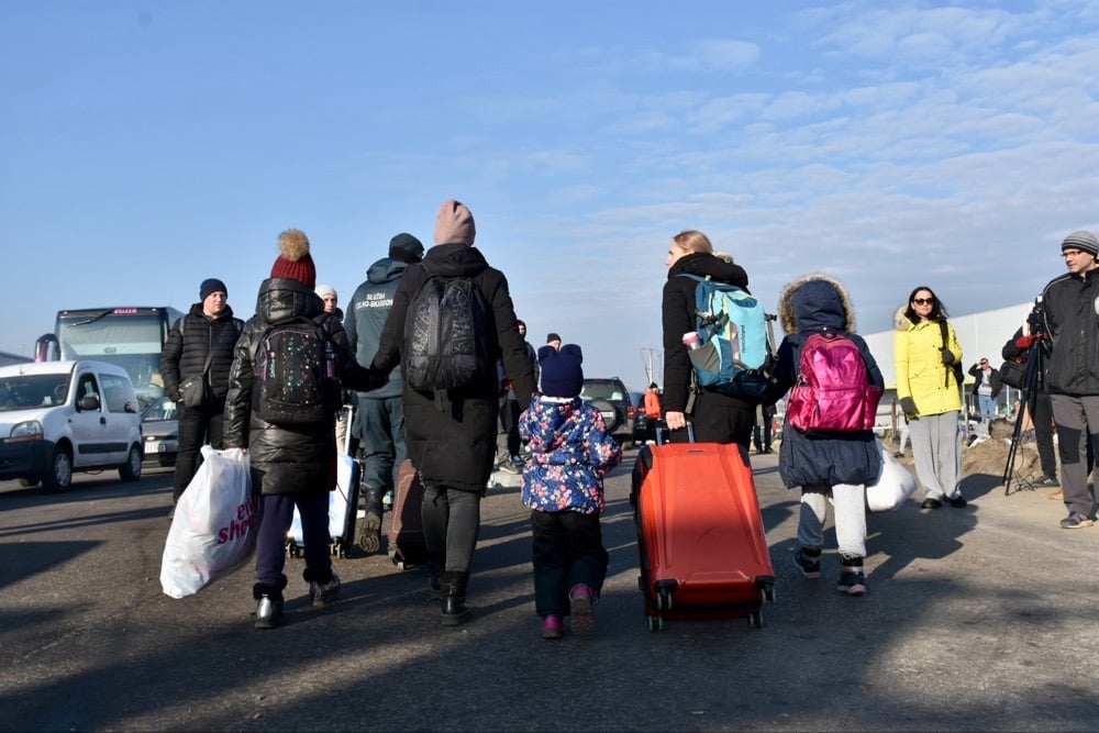 Families steken met hun bagage de grens bij Zosin, Polen op de vlucht voor het geweld in Oekraïne. © UNHCR/Chris Melzer