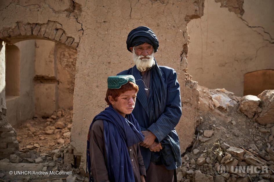 Sayed Mohammad* (70) en zijn zoon Adbul Wadood* (13) staan in hun verwoest huis in Marja, in Helmand Provincie, zuid Afghanistan. Sayed Mohammad, zijn vrouw en hun zes kinderen ontvluchtten hun thuis toen de vijandelijkheden dicht in hun buurt kwamen in juli 2021. Ze zijn nu teruggekeerd om hun huis herop te bouwen. * namen werden veranderd om veiligheid te beschermen