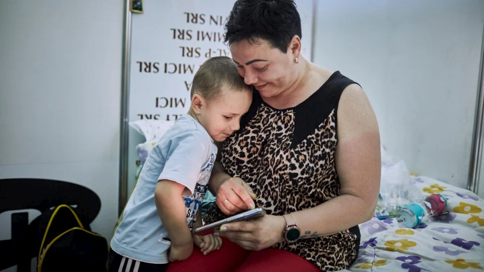 Antonina* en haar zoon Artem kijken naar een familiefoto in hun onderkomen in het vluchtelingencentrum in Chisinau, Moldavië. *Antonia nam geen deel aan de bevraging. © UNHCR/Andrew McConnell