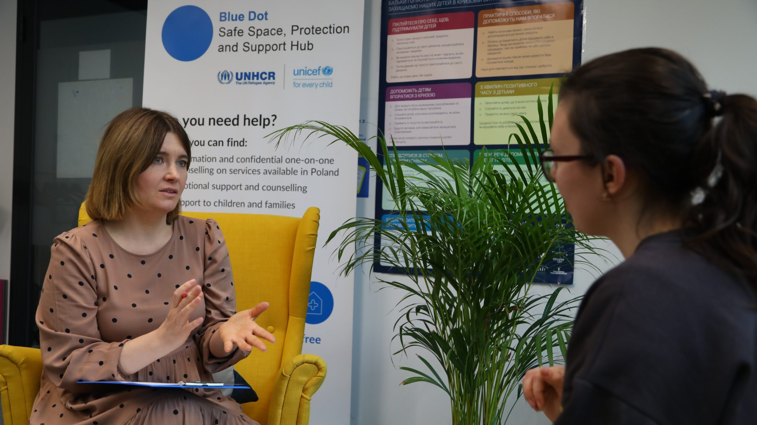 La psychologue ukrainienne Inna Chapko (à gauche) fournit des informations sur les services psychosociaux dans un centre Point Bleu à Varsovie. © HCR/Tarik Argaz