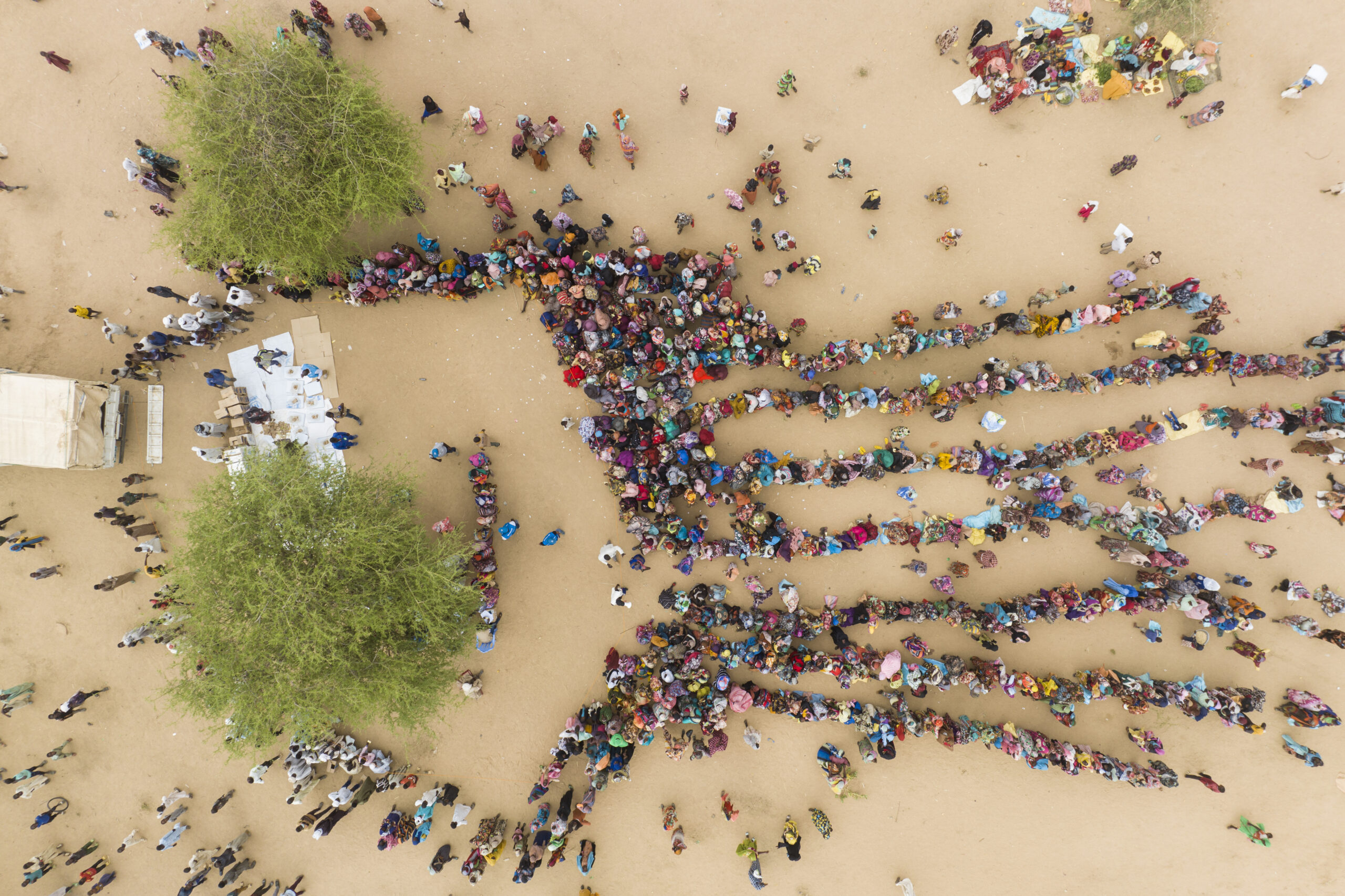 Een luchtfoto van hulpgoederen die worden uitgedeeld aan zonet aangekomen Soedanese vluchtelingen in Madjigilta in Tsjaad. © UNHCR/Colin Delfosse