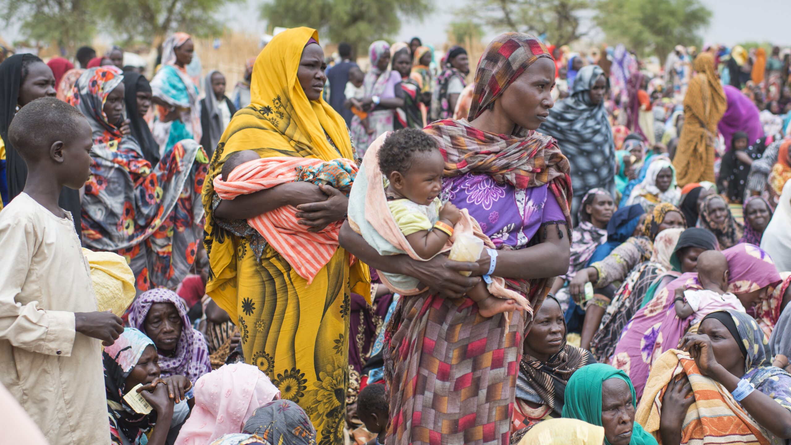 Honderden Soedanese vluchtelingen die zopas de grens met Tsjaad hebben overgestoken, verzamelen zich om hulpgoederen van UNHCR in ontvangst te nemen in Madjigilta in de regio Ouaddaï, Tsjaad. © UNHCR/Colin Delfosse