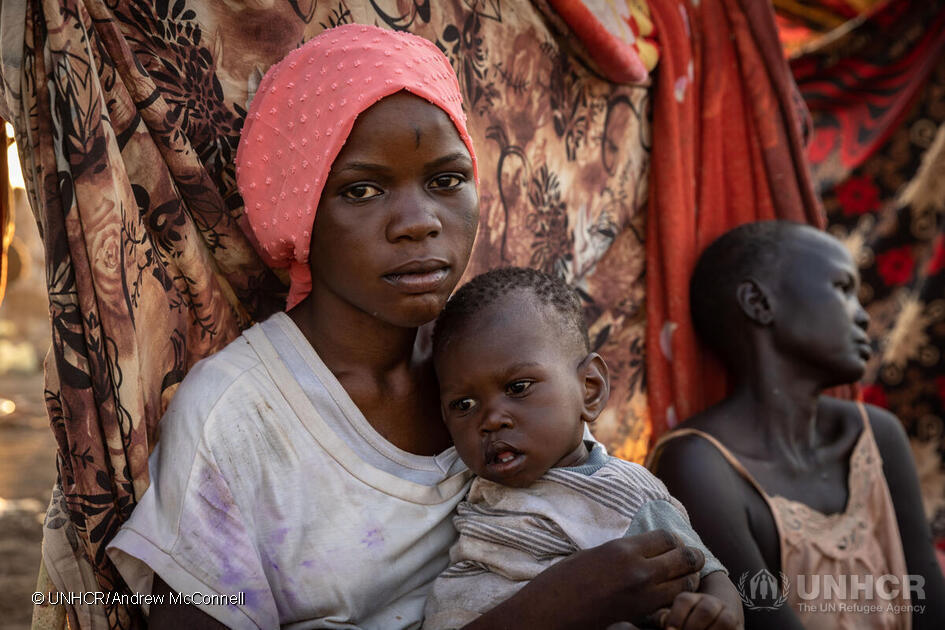 De Zuid-Soedanese Nyauke Chianjiak, 18, zit met haar eenjarige zusje Kuoli in een transitcentrum in Renk, Zuid-Soedan, nadat ze het conflict in Soedan is ontvlucht en teruggekeerd is naar Zuid-Soedan. © UNHCR/Andrew McConnell