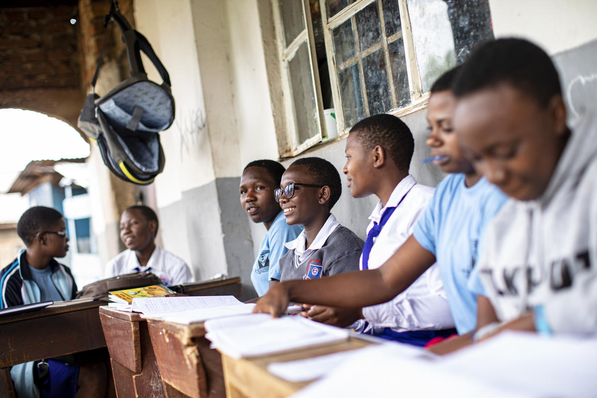 Enhakole sits in a classroom next to other pupils..