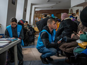 UNHCR workers speak to refugees from Ukraine inside a public buiding.